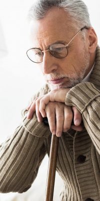 pensive retired man thinking while holding walking stick